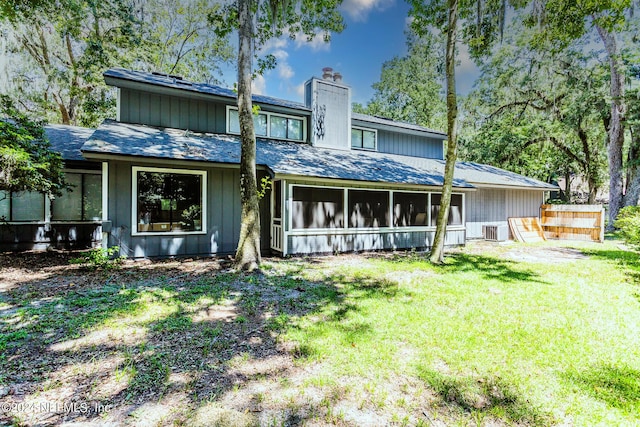 back of house with a lawn, a sunroom, a chimney, fence, and central AC