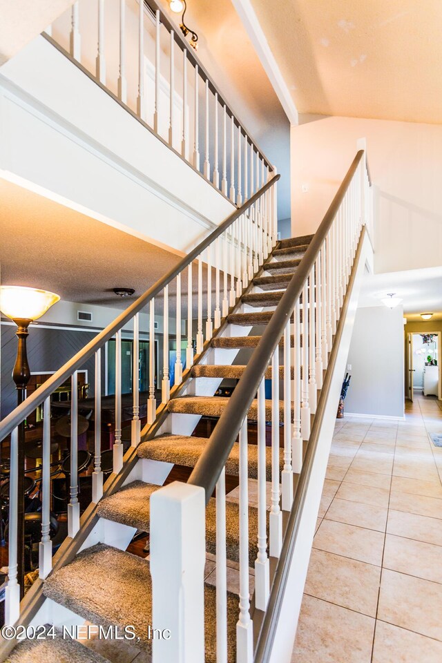 staircase featuring tile patterned flooring and a high ceiling