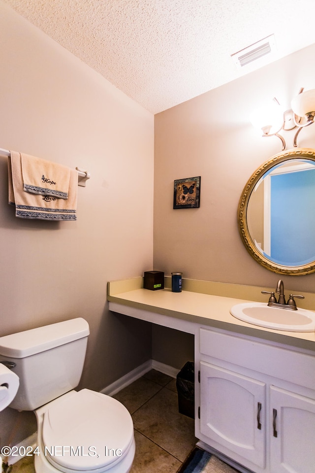 bathroom with tile patterned flooring, a textured ceiling, vanity, and toilet