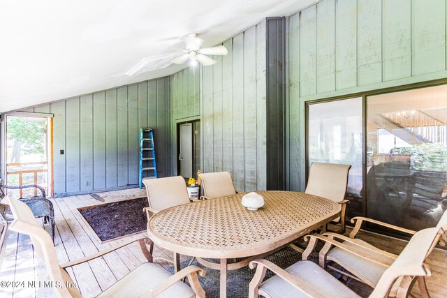 dining area with ceiling fan, wooden walls, lofted ceiling, and hardwood / wood-style floors