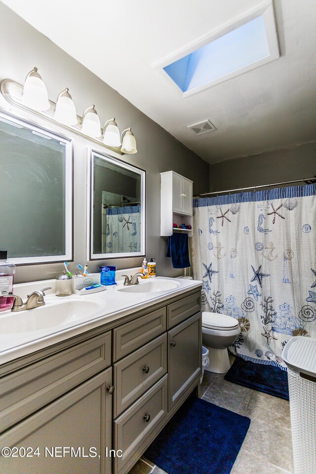 bathroom featuring a skylight, toilet, tile patterned flooring, and vanity