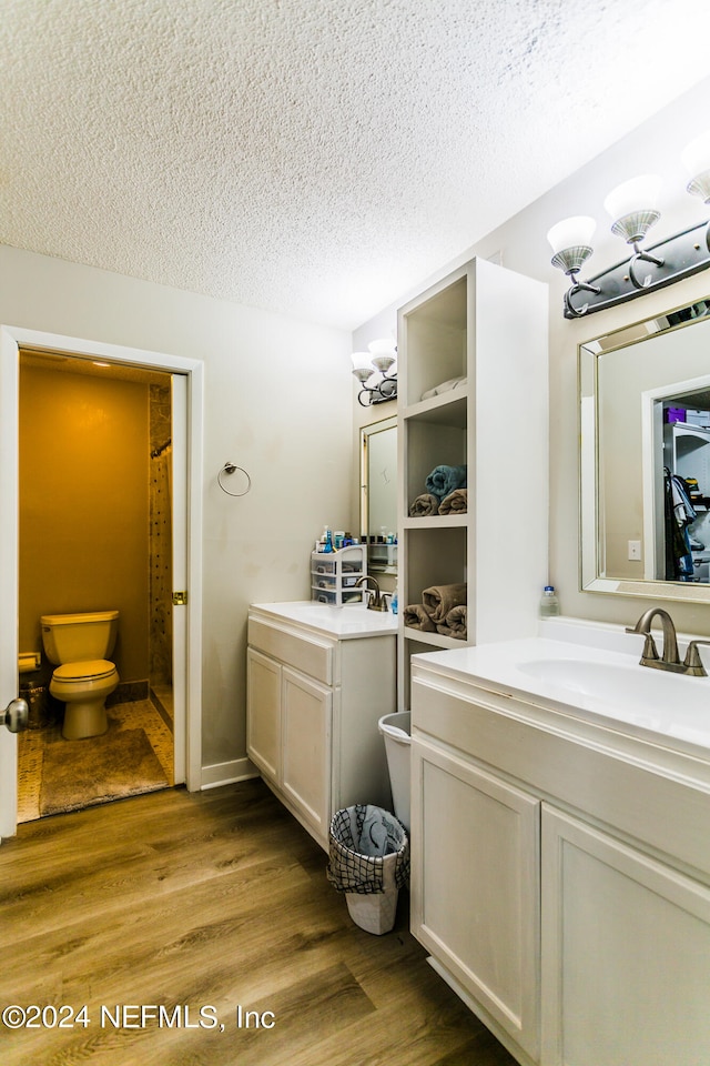 bathroom featuring a textured ceiling, vanity, hardwood / wood-style floors, and toilet