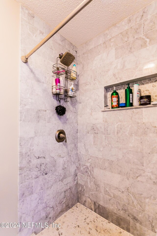 bathroom with a textured ceiling and a tile shower