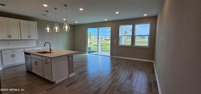 kitchen with decorative light fixtures, white cabinets, a kitchen island with sink, and sink