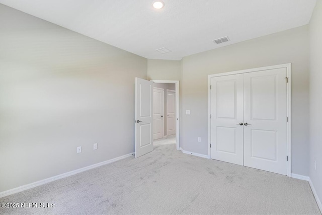 unfurnished bedroom with light colored carpet and a closet