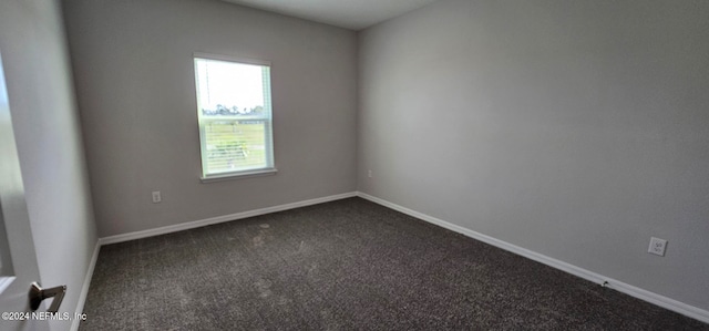 spare room featuring dark carpet