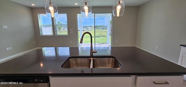 kitchen with hanging light fixtures, sink, stainless steel dishwasher, and white cabinets