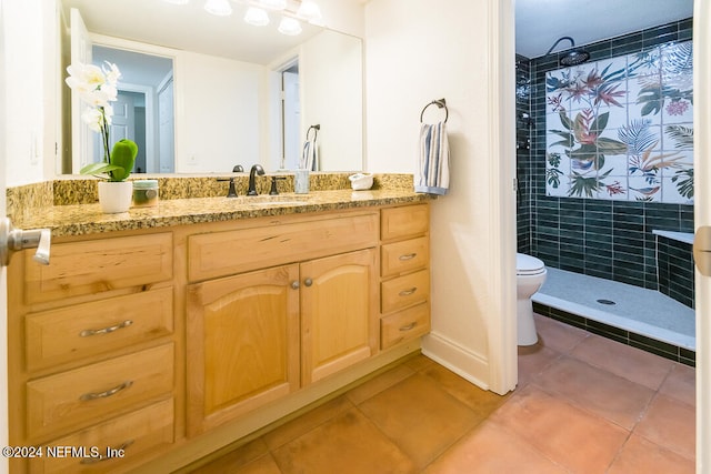 bathroom with a tile shower, toilet, tile patterned floors, and vanity