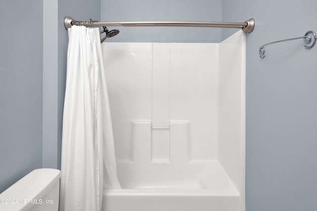 bathroom with toilet and shower / bathtub combination with curtain