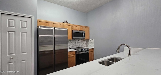 kitchen with decorative backsplash, stainless steel appliances, sink, and a textured ceiling