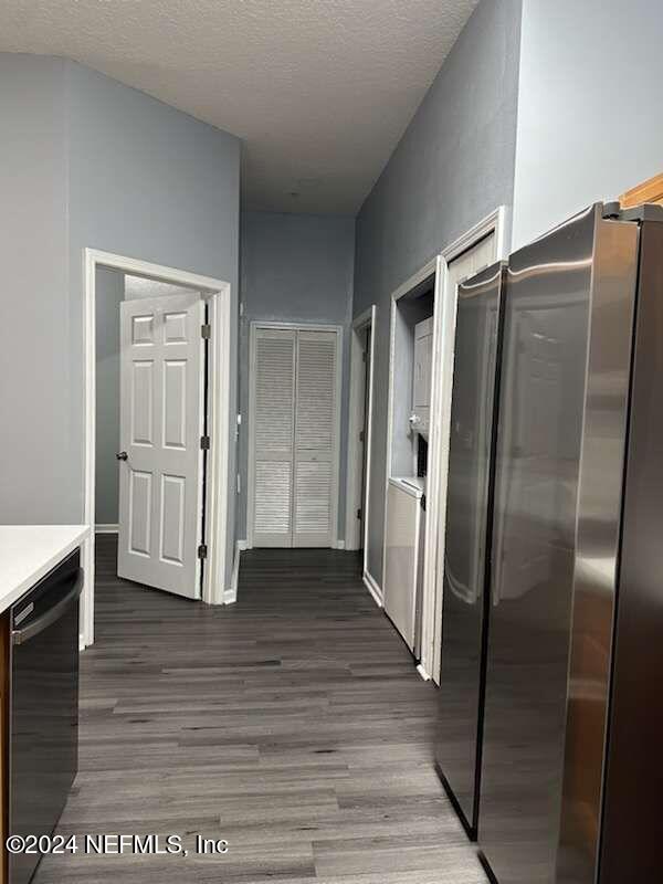 hall with a textured ceiling and dark hardwood / wood-style floors