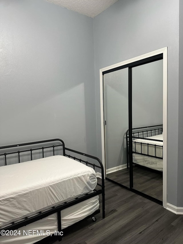 bedroom with dark wood-type flooring, a textured ceiling, and a closet