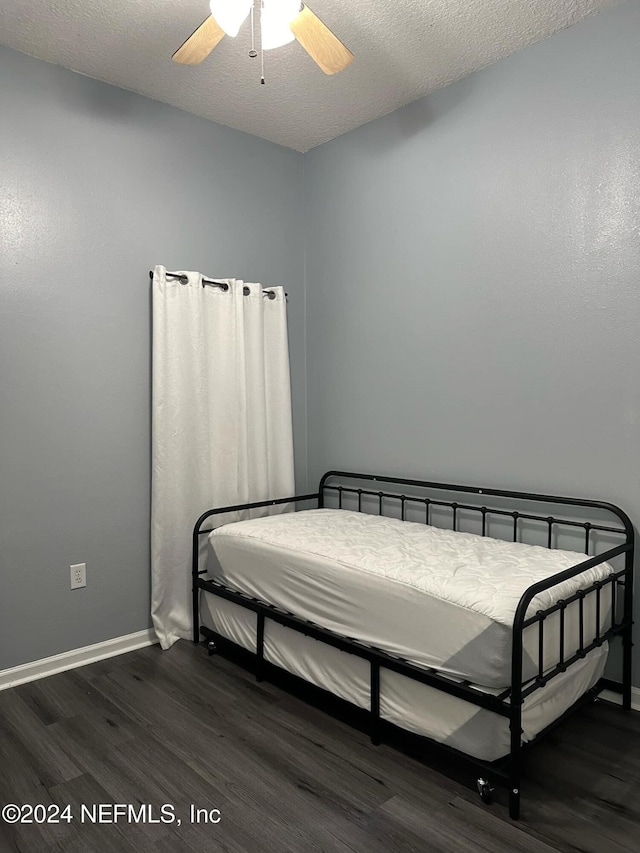 bedroom featuring dark hardwood / wood-style flooring, a textured ceiling, and ceiling fan