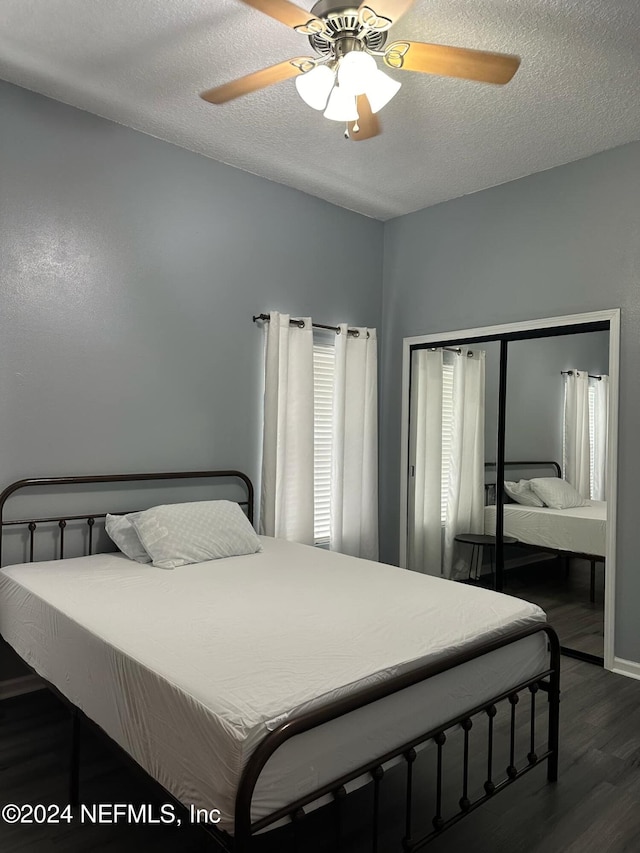 bedroom featuring dark wood-type flooring, a textured ceiling, and ceiling fan