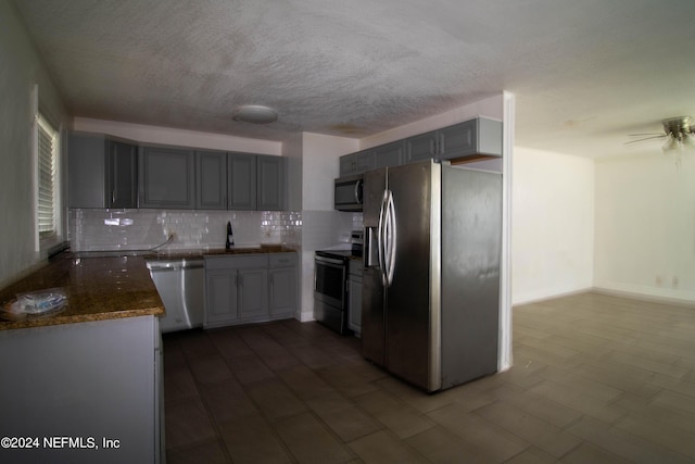 kitchen with appliances with stainless steel finishes, sink, gray cabinetry, ceiling fan, and tasteful backsplash