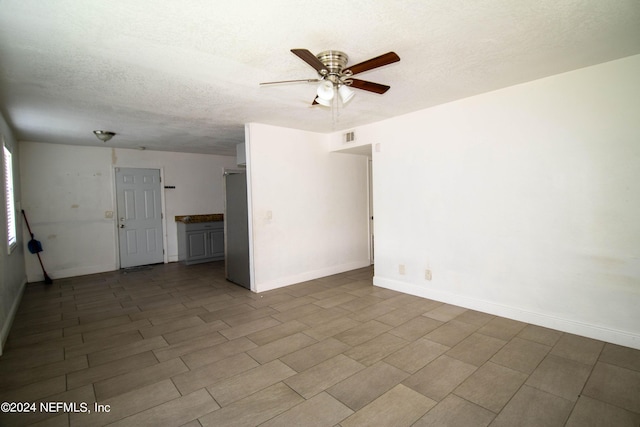 empty room featuring ceiling fan and a textured ceiling