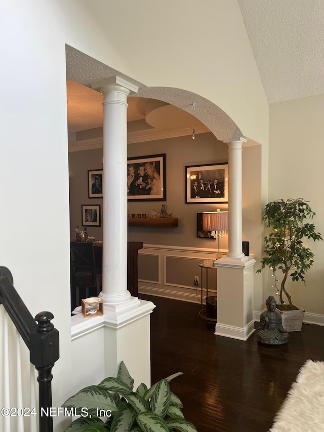 hallway featuring lofted ceiling, ornamental molding, a textured ceiling, decorative columns, and dark hardwood / wood-style flooring