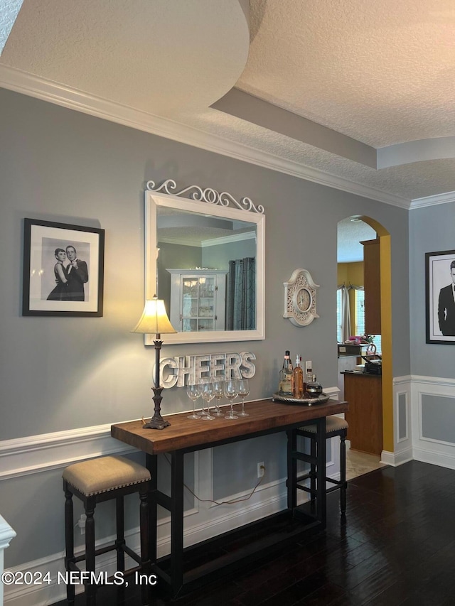 interior space with ornamental molding, a tray ceiling, wood-type flooring, and a textured ceiling