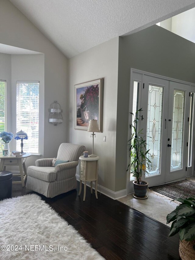 foyer entrance featuring french doors, a textured ceiling, lofted ceiling, and dark wood-type flooring