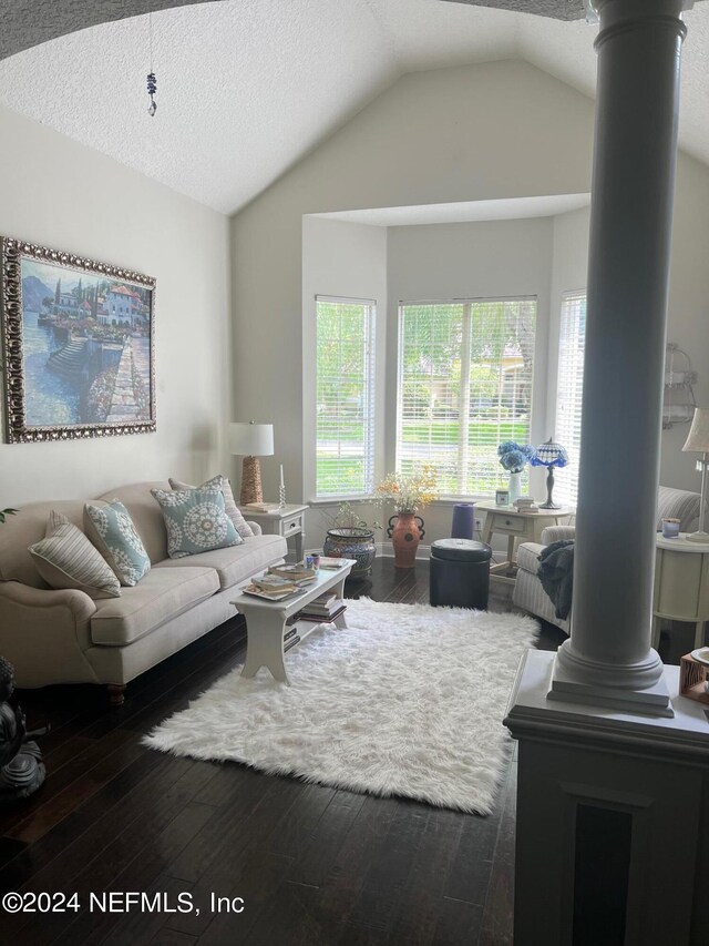 living room featuring lofted ceiling, ornate columns, dark hardwood / wood-style flooring, and a textured ceiling