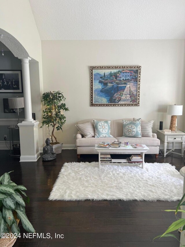 living room featuring a textured ceiling, dark wood-type flooring, decorative columns, and lofted ceiling