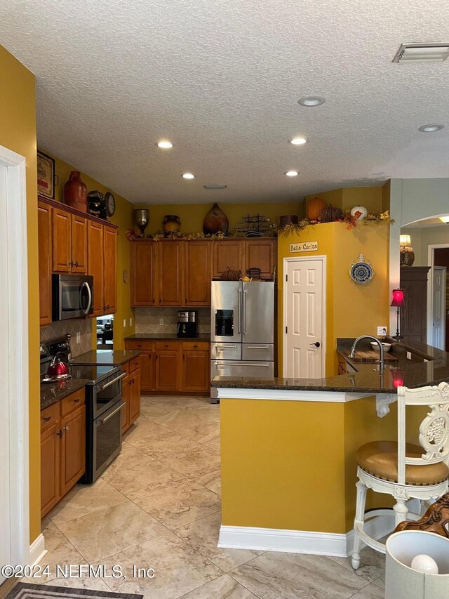 kitchen featuring tasteful backsplash, sink, stainless steel appliances, kitchen peninsula, and a kitchen bar