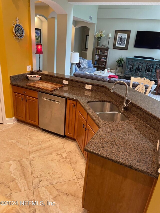 kitchen featuring dishwasher, dark stone counters, and sink