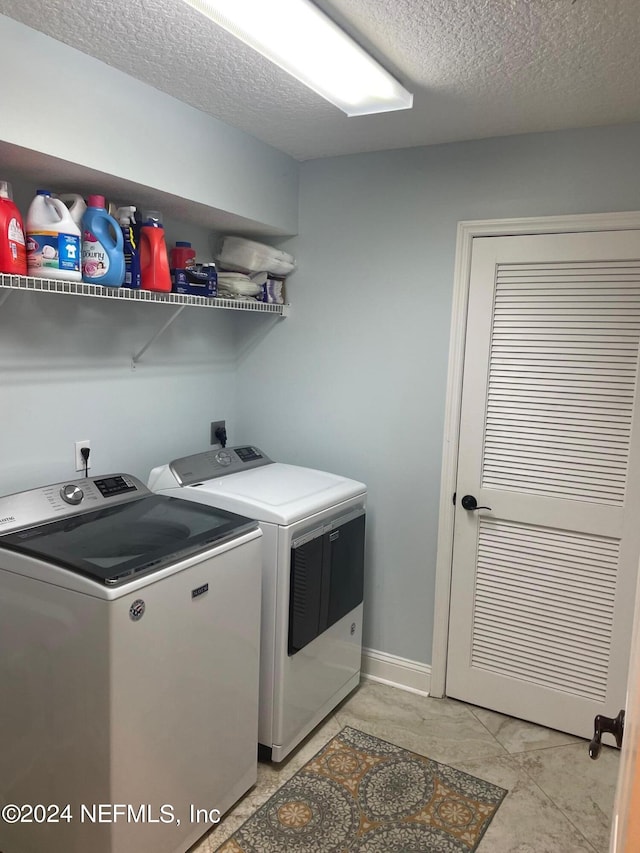 clothes washing area featuring a textured ceiling and washing machine and clothes dryer