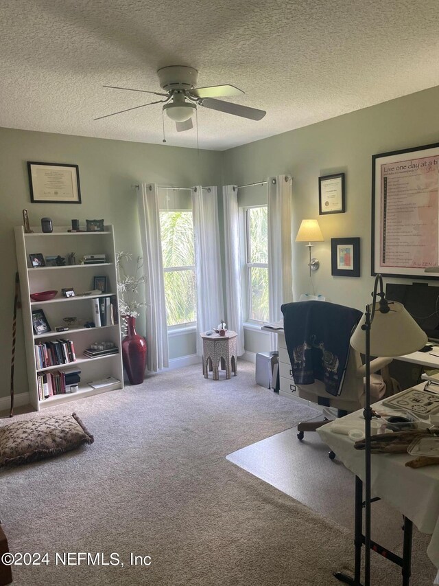 carpeted office featuring ceiling fan and a textured ceiling