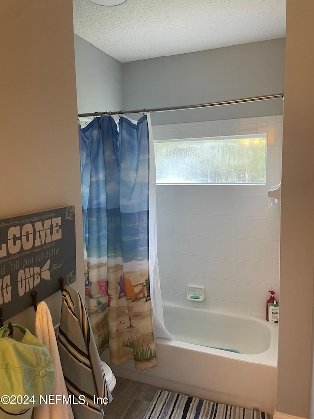 bathroom featuring a textured ceiling, shower / tub combo, hardwood / wood-style floors, and a wealth of natural light