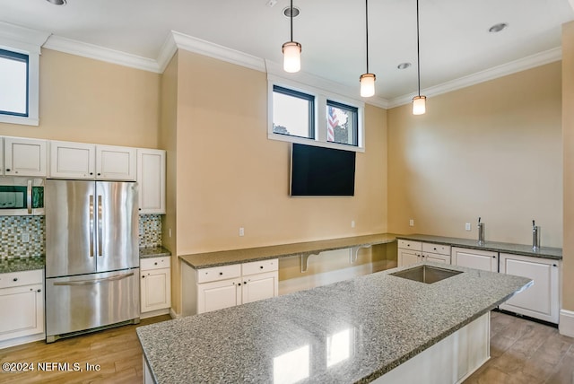 kitchen with decorative light fixtures, appliances with stainless steel finishes, dark stone counters, and light hardwood / wood-style flooring