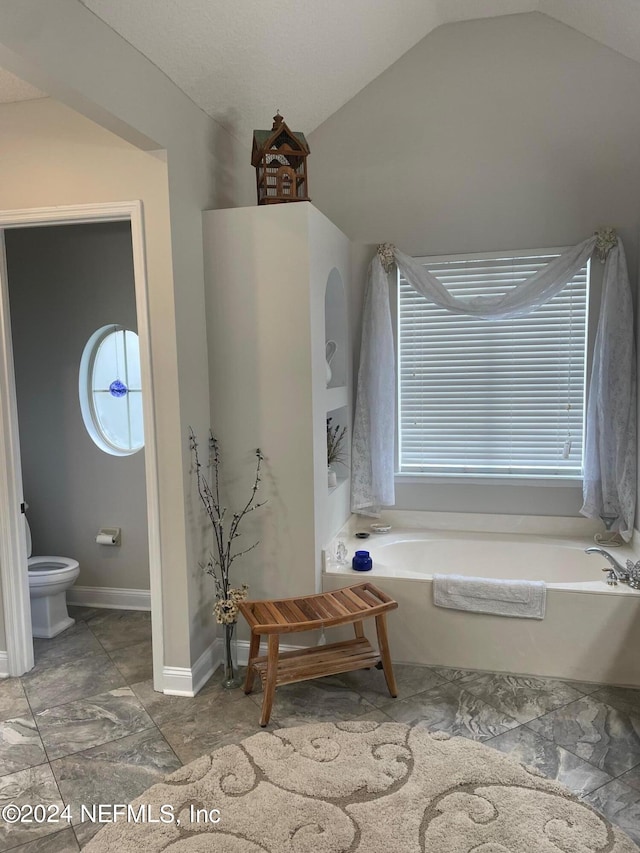 bathroom featuring lofted ceiling, a tub, and toilet