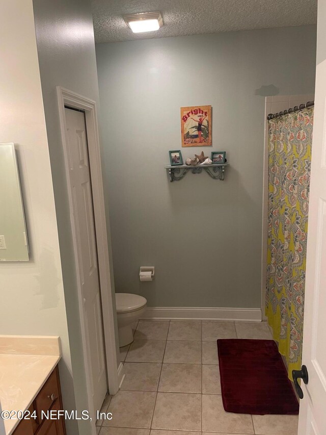 bathroom featuring tile patterned flooring, a textured ceiling, vanity, and toilet