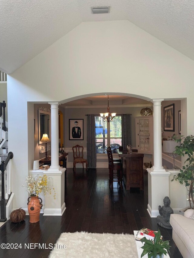 living room with lofted ceiling, a textured ceiling, decorative columns, a notable chandelier, and dark hardwood / wood-style flooring