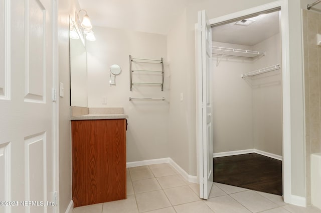 full bath with a walk in closet, vanity, baseboards, and tile patterned floors