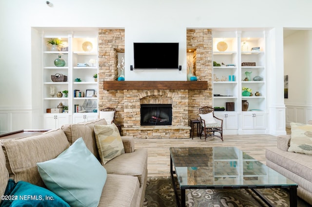 living area featuring built in shelves, a decorative wall, a wainscoted wall, a fireplace, and wood finished floors