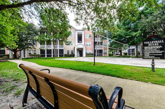 view of property's community with a lawn and volleyball court