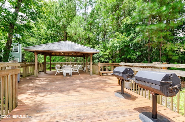 wooden deck featuring outdoor dining area, area for grilling, and a gazebo