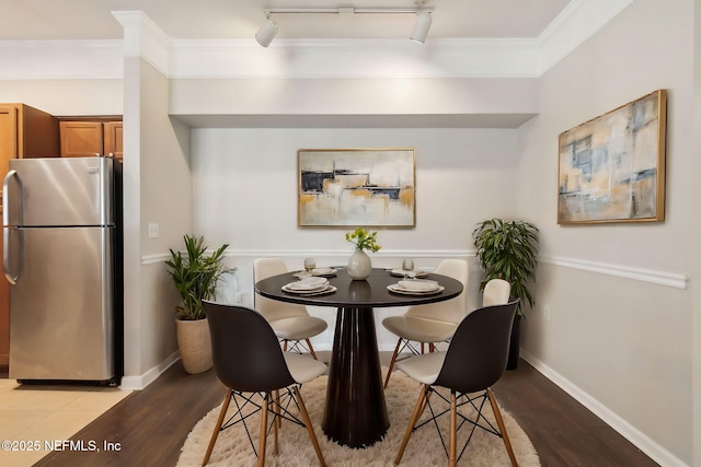 dining space featuring ornamental molding, light wood finished floors, and baseboards