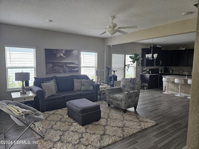 living room featuring ceiling fan, a textured ceiling, and wood finish floors