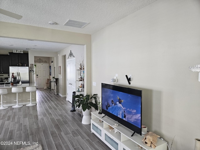 living room featuring a textured ceiling, baseboards, visible vents, and wood tiled floor