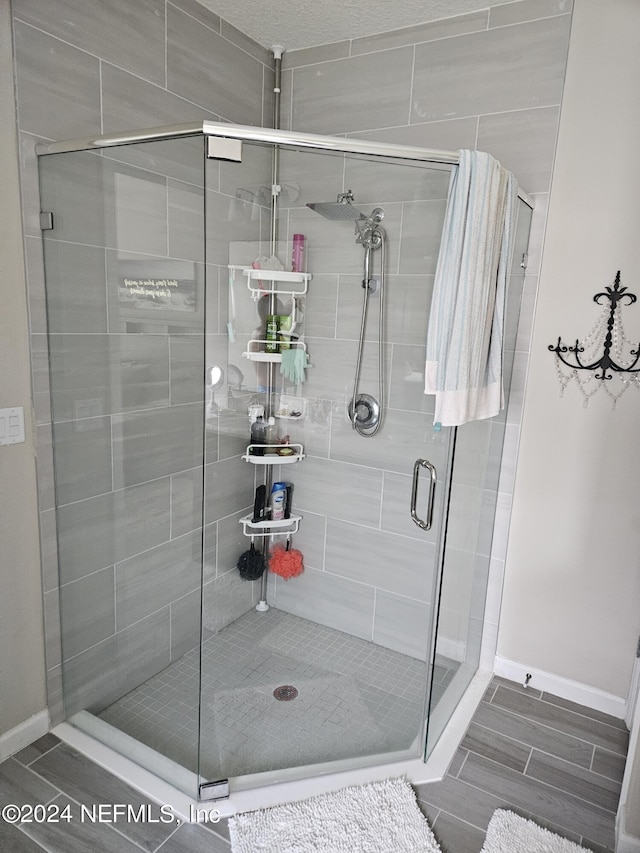 bathroom with a shower stall, wood tiled floor, and baseboards