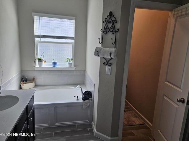 full bath with a garden tub, plenty of natural light, vanity, and wood finish floors