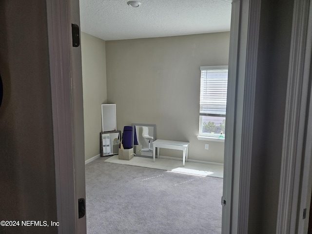 unfurnished bedroom with a textured ceiling, baseboards, and carpet flooring