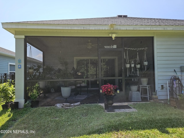 doorway to property with a patio area, a shingled roof, and a lawn