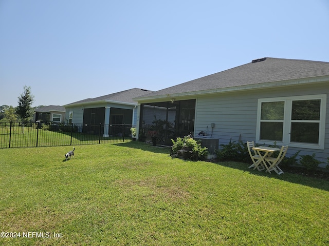 back of property with a yard, fence, a sunroom, and central air condition unit