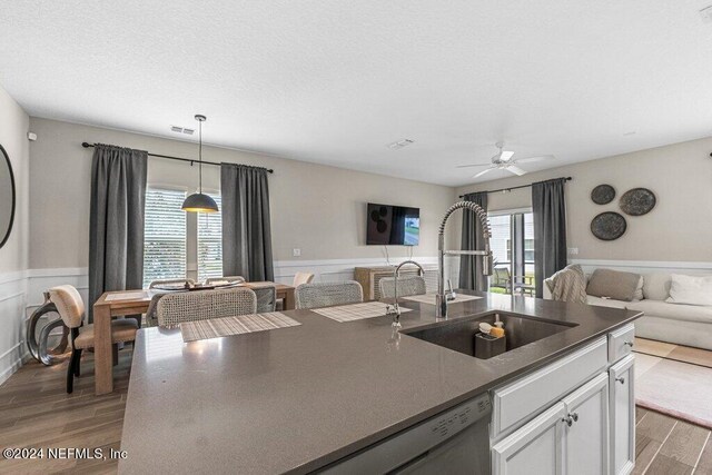 kitchen featuring hardwood / wood-style floors, ceiling fan, white cabinetry, pendant lighting, and sink