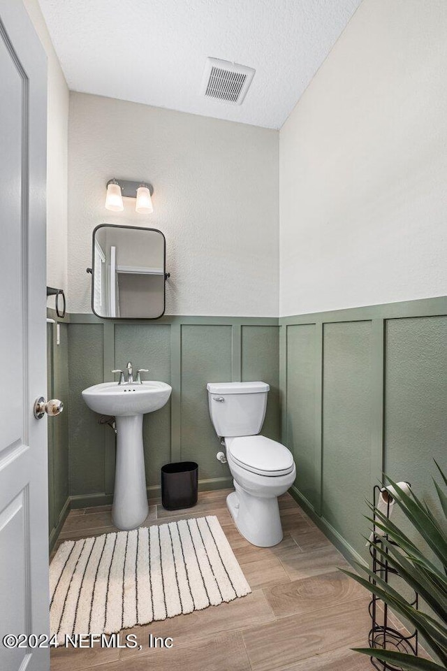 bathroom featuring a textured ceiling, toilet, and hardwood / wood-style flooring