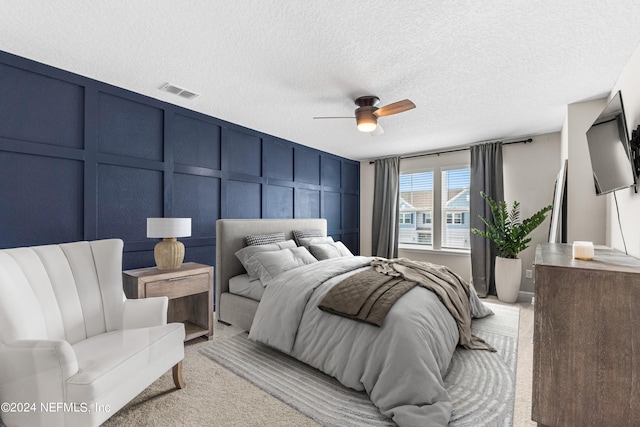 carpeted bedroom with ceiling fan and a textured ceiling