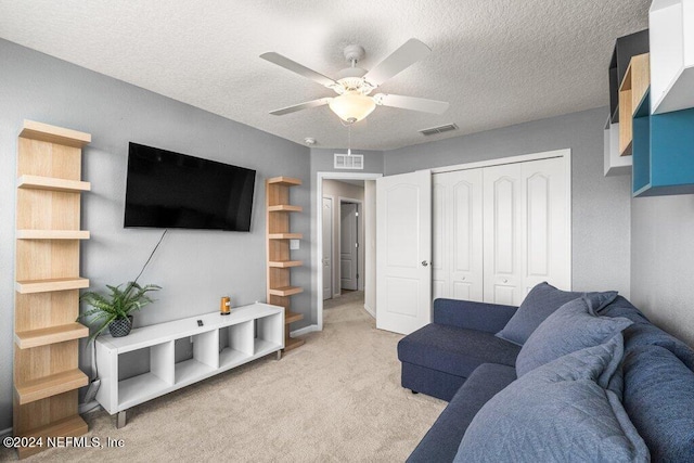 carpeted living room featuring ceiling fan and a textured ceiling